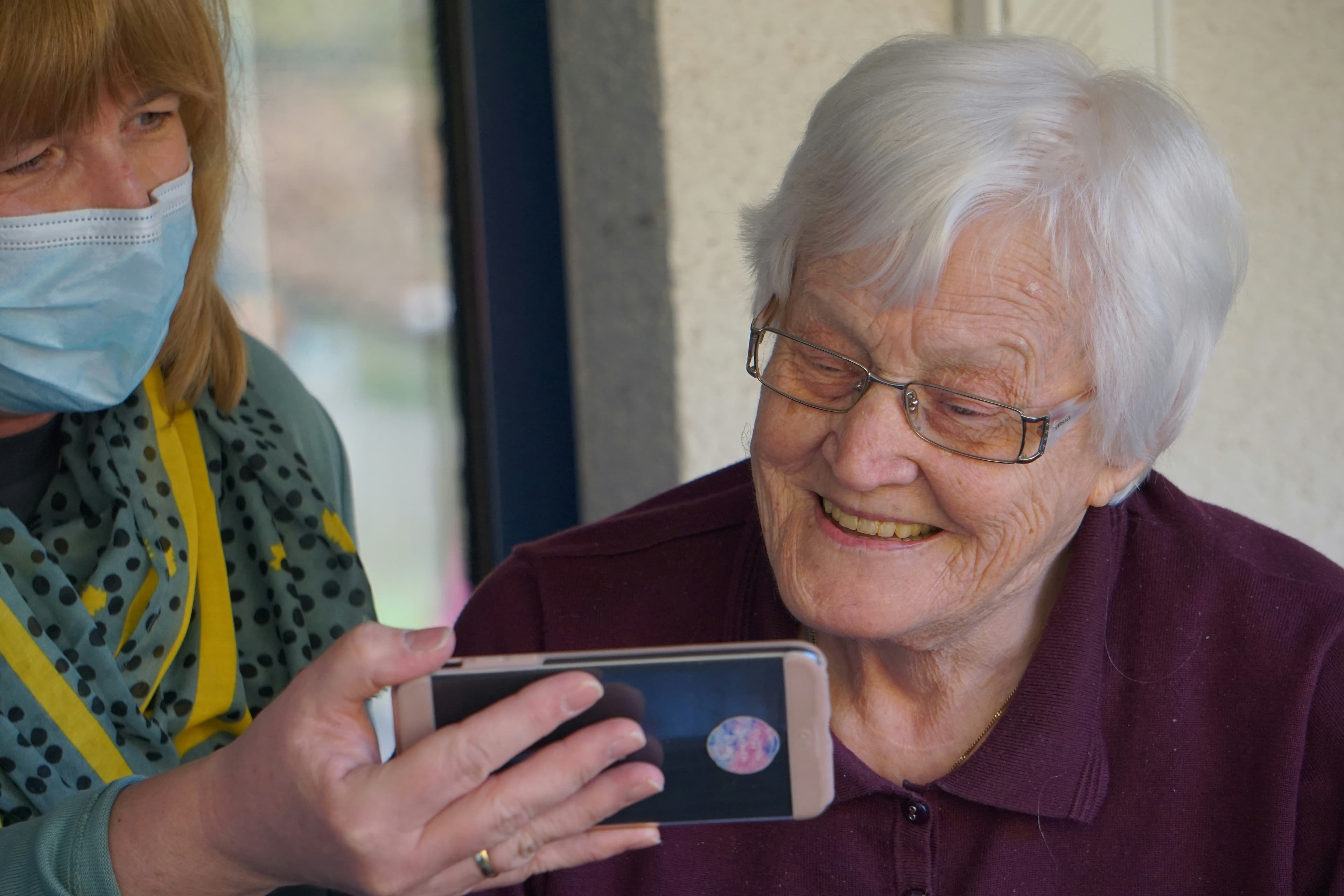 Caregiver helping an older adult use a smartphone